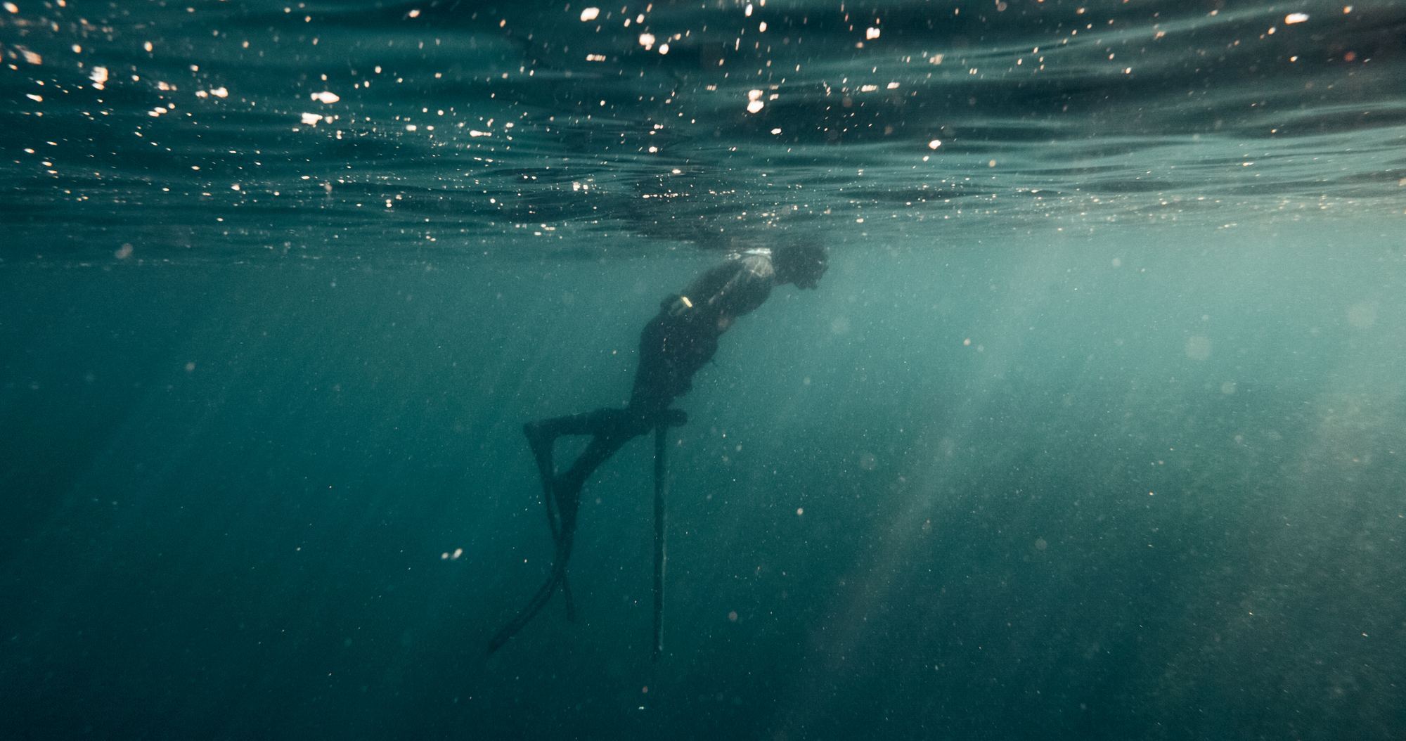 Freediver underwater with foil board and light rays