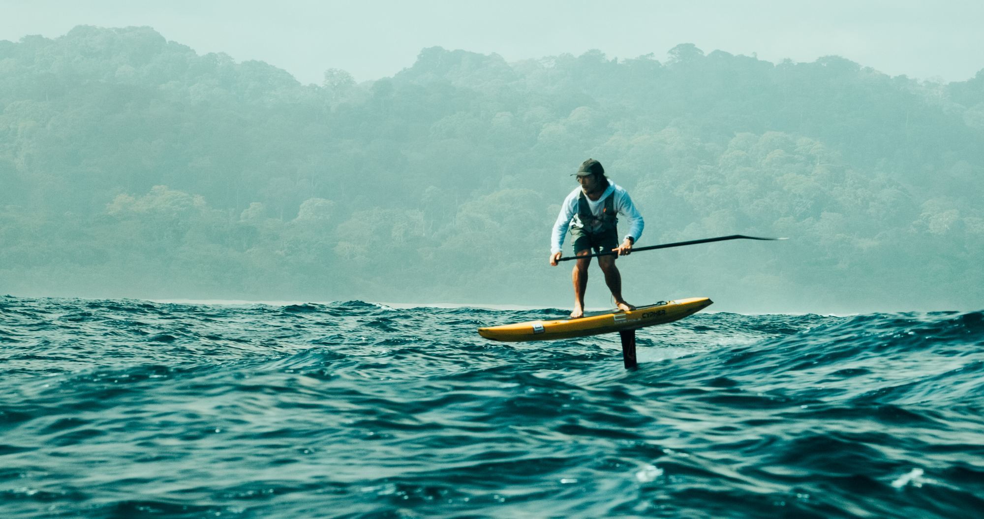Paddler on foil board on choppy grey ocean minimal
