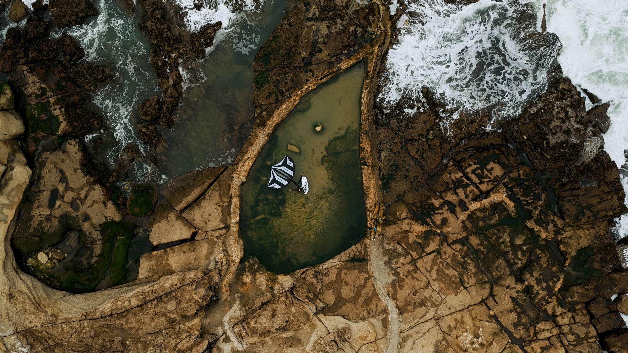 Aerial drone shot of wing foiler on dark green ocean