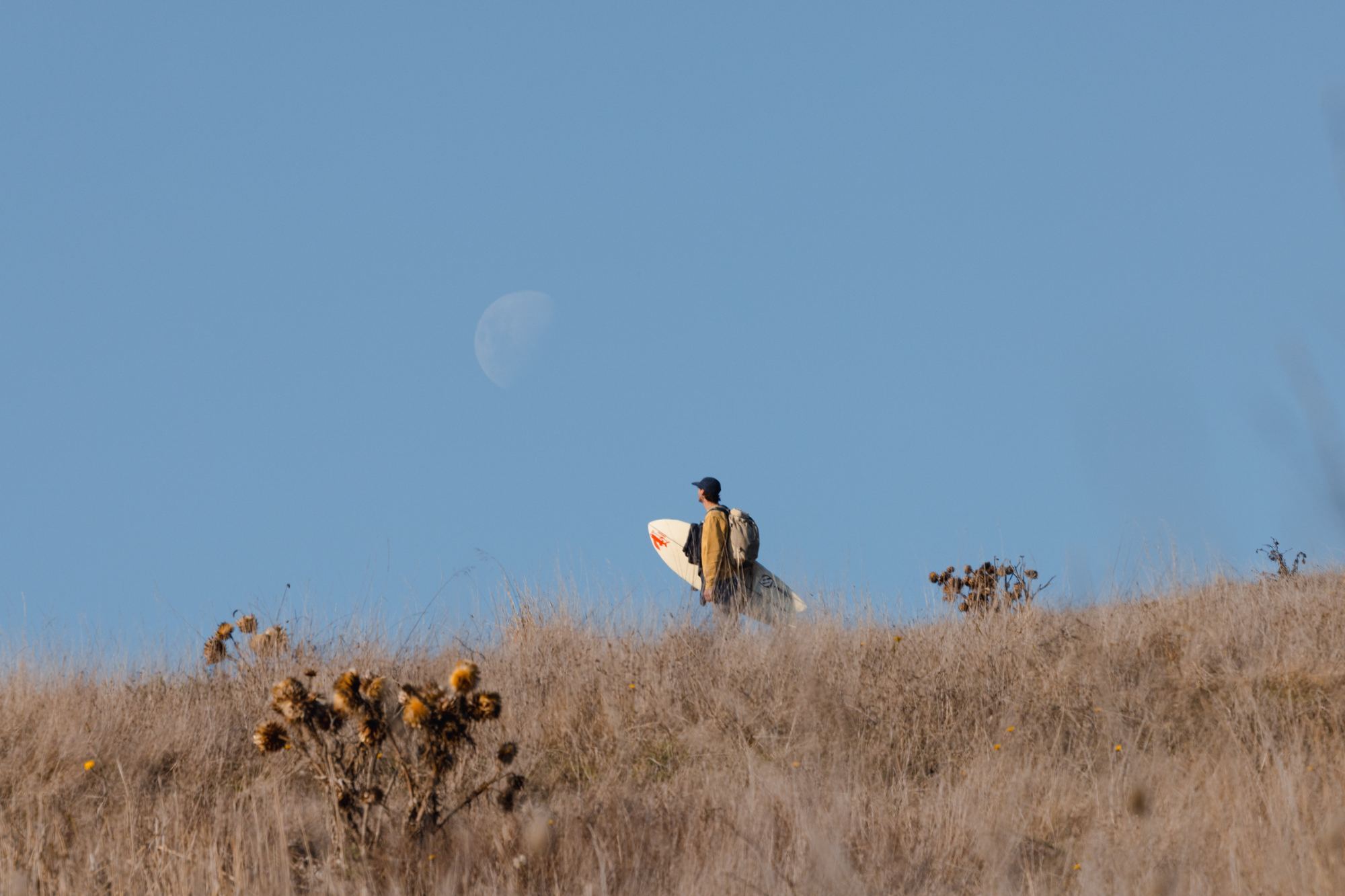 Surfer walking with board under moon Chile